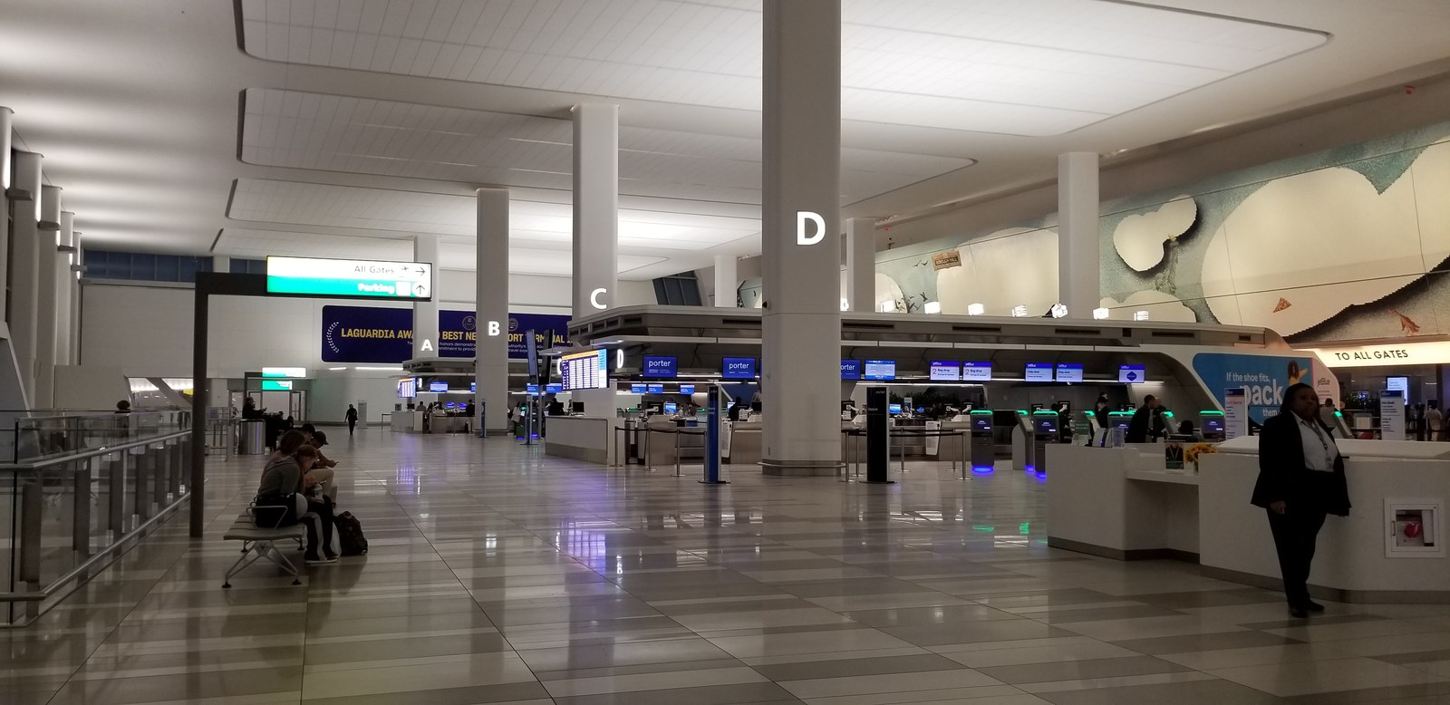Interior photograph of the Terminal B Level 3 ticketing and check-in hall in October 2025, with check-in locations A to D, self-service kiosks, and the mosaic wall